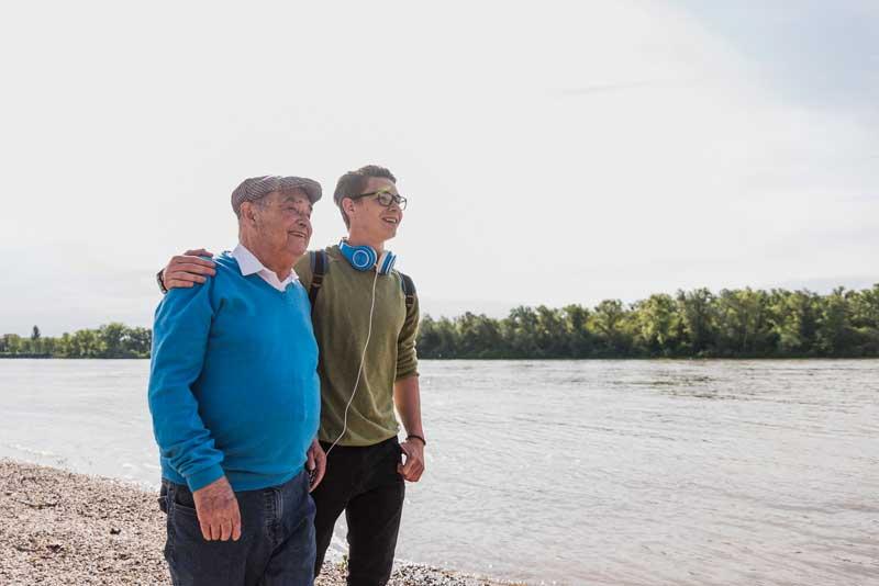 Grandfather and grandson walking by a lake